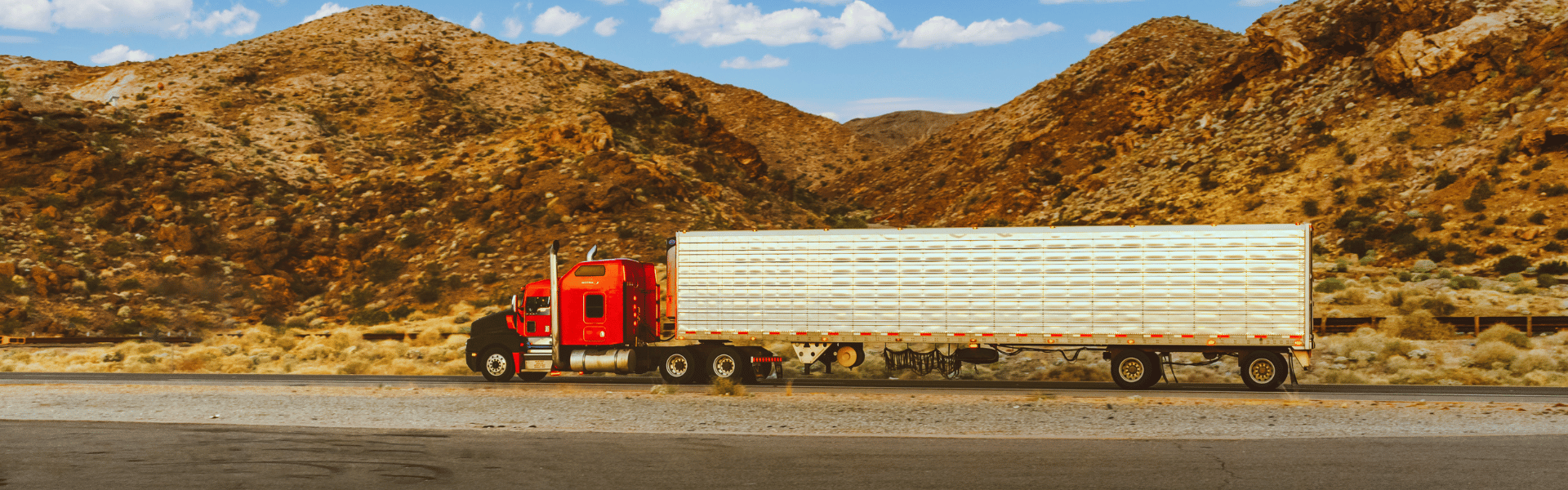 semi truck on road with mountains in the background