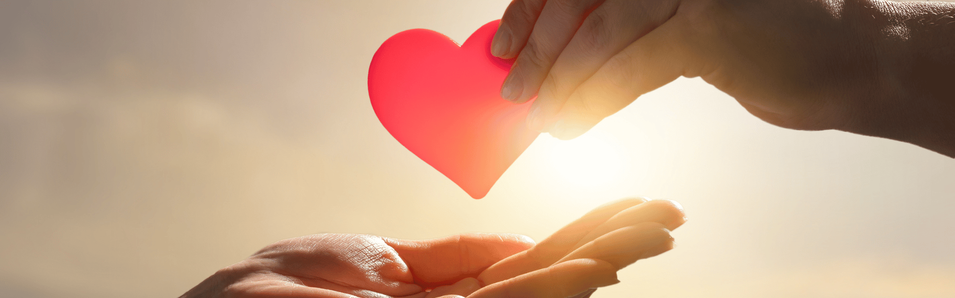 Hand giving heart to a receiving hand