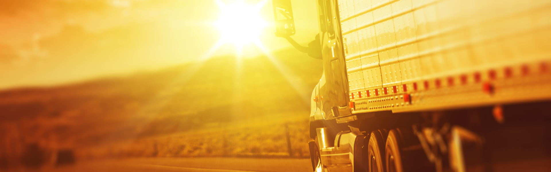 semi truck driving into bright sunset