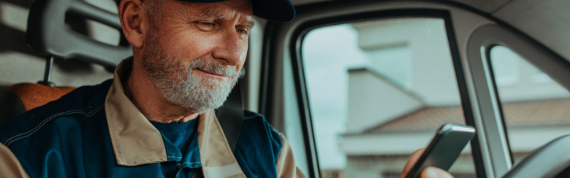 older trucker looking at phone in cab
