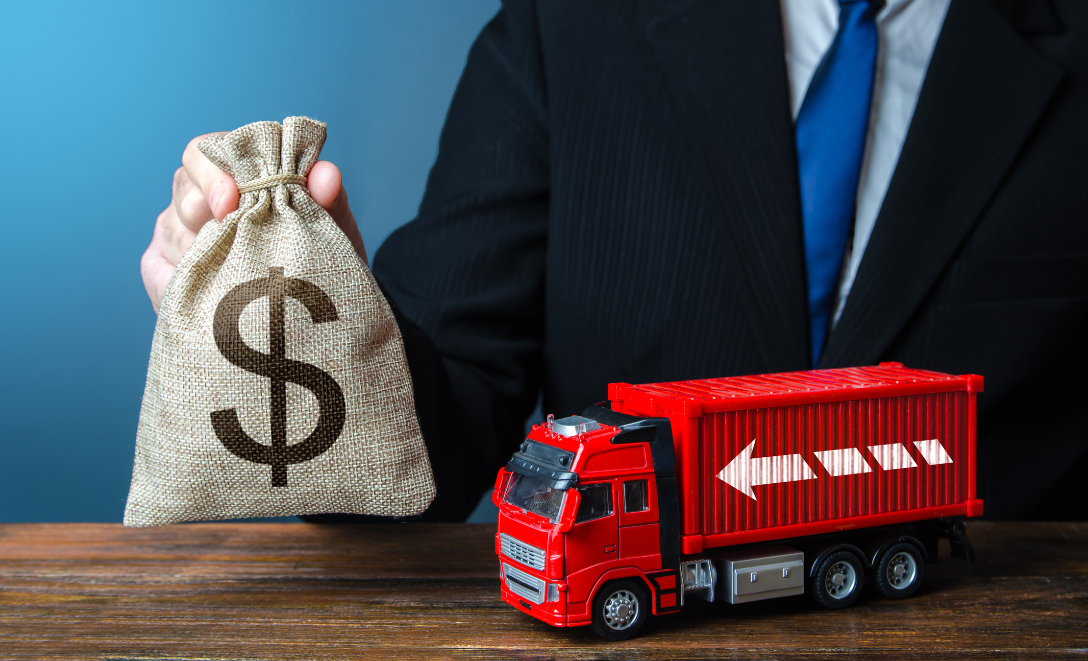 Businessman with dollar money bag and truck. High income of the transport business and the transport of goods. Good salaries for drivers. Rising prices, global containers shortage crisis. Logistics