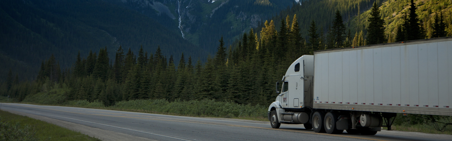 semi truck on road with mountains in background