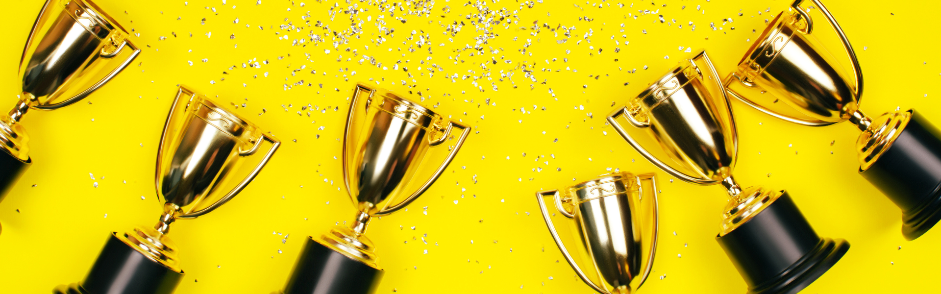 trophies and confetti on yellow background