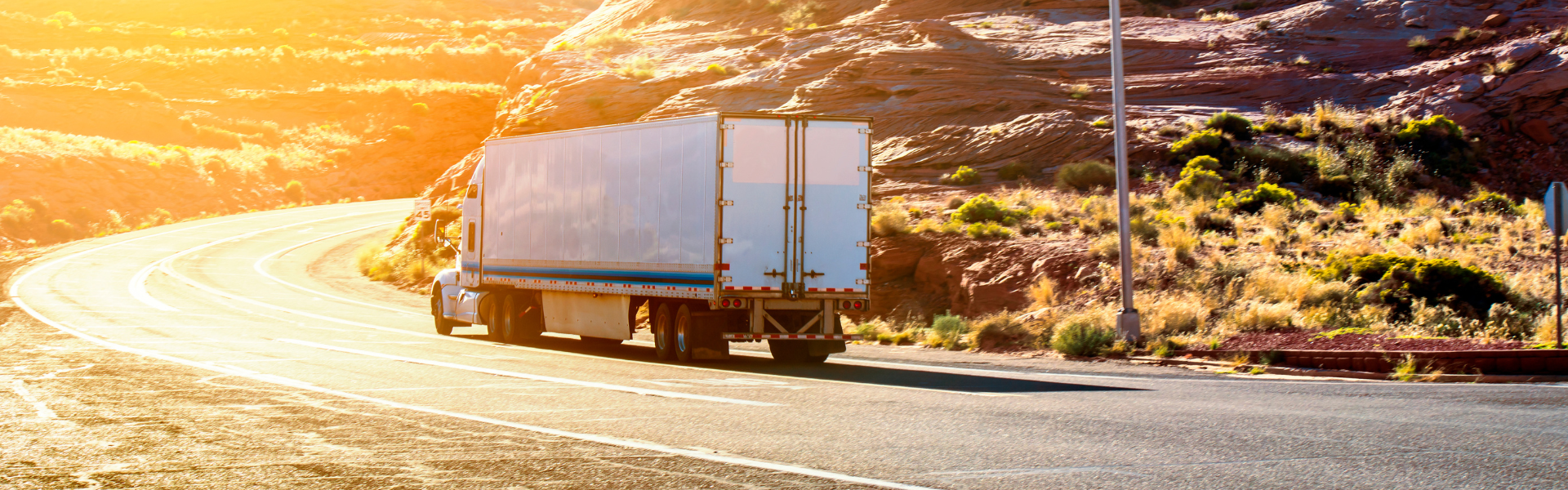 semi truck on curvy mountain road at sunrise