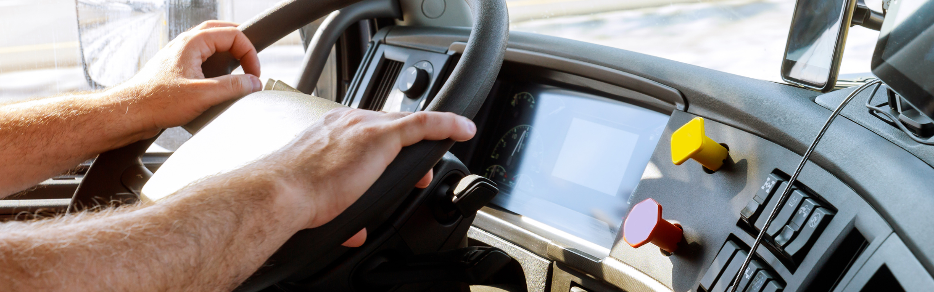 man's hands on the wheel of a semi truck from an in-cab perspective