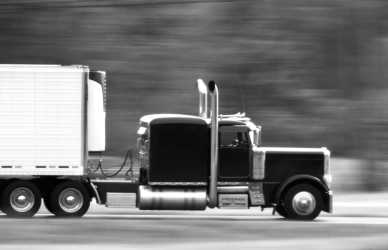 black and white photo of semi truck driving on road