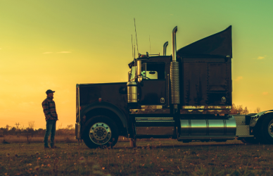 man standing near semi truck at sunset