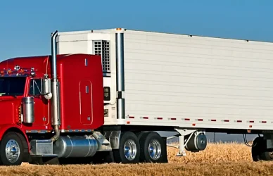 red semi truck with white trailer on road