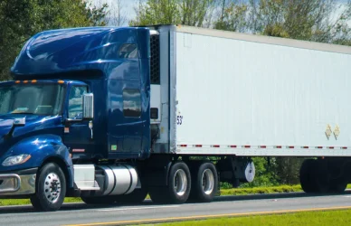 dark blue semi truck pulling white trailer