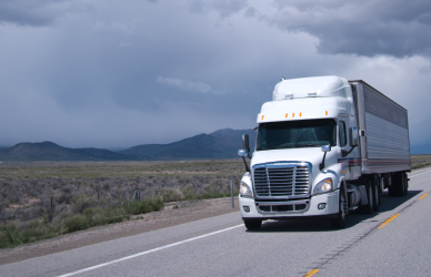 white semi truck on road with cloudy skies in the background