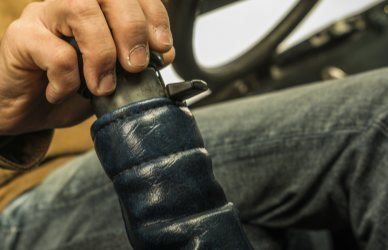 trucker with hand on gear shift in semi truck cab, of floating gears in your semi-truck with expert tips on throttle control, timing, and avoiding forced shifts