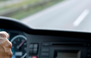 driver behind the wheel of semi truck looking forward through dash