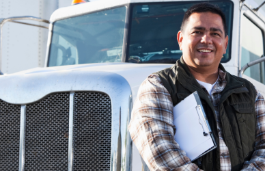 man with clipboard leaning against semi truck