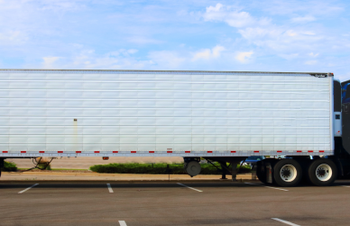 blue semi truck with white trailer parked in retail parking lot